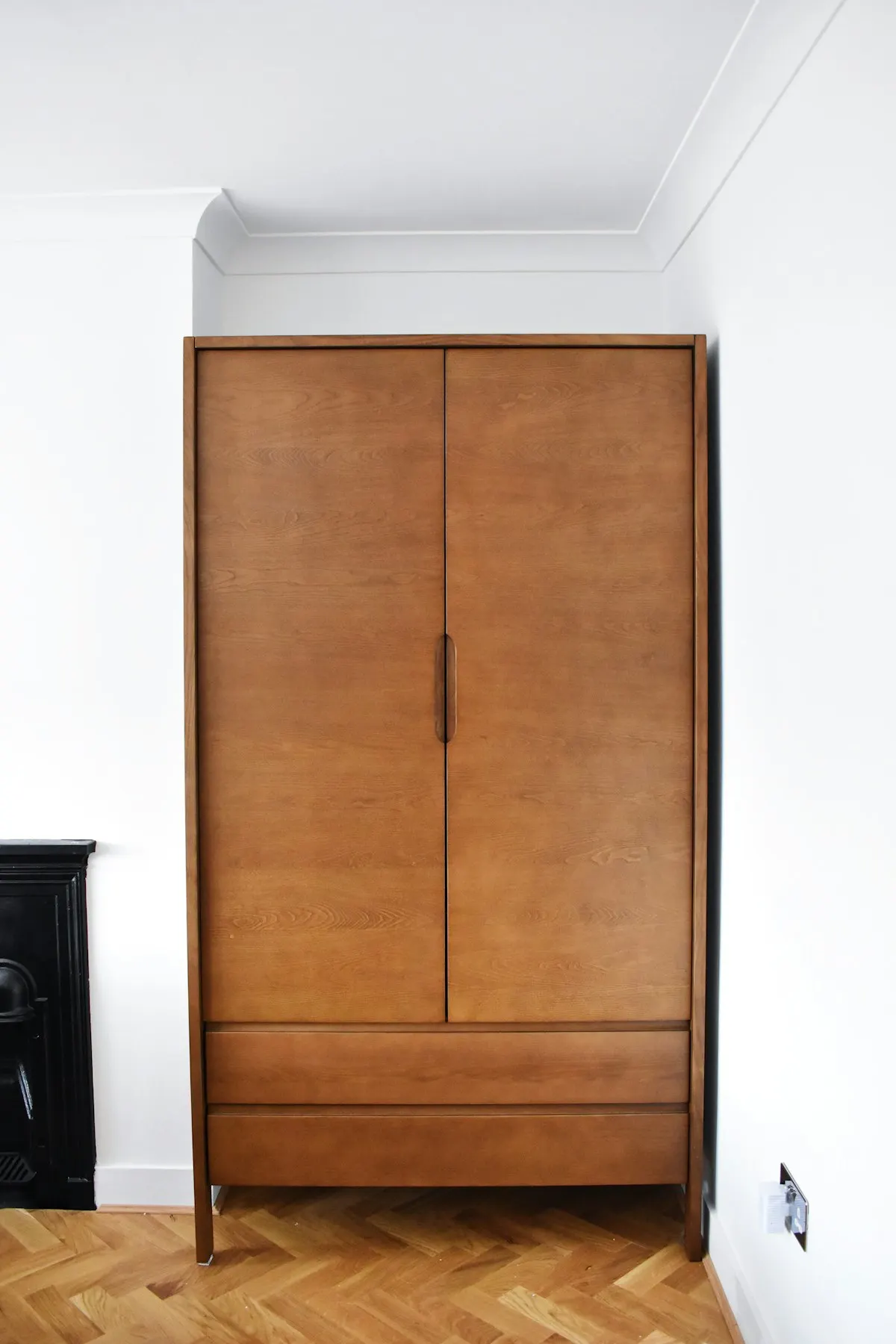Freestanding timber wardrobe against a white wall