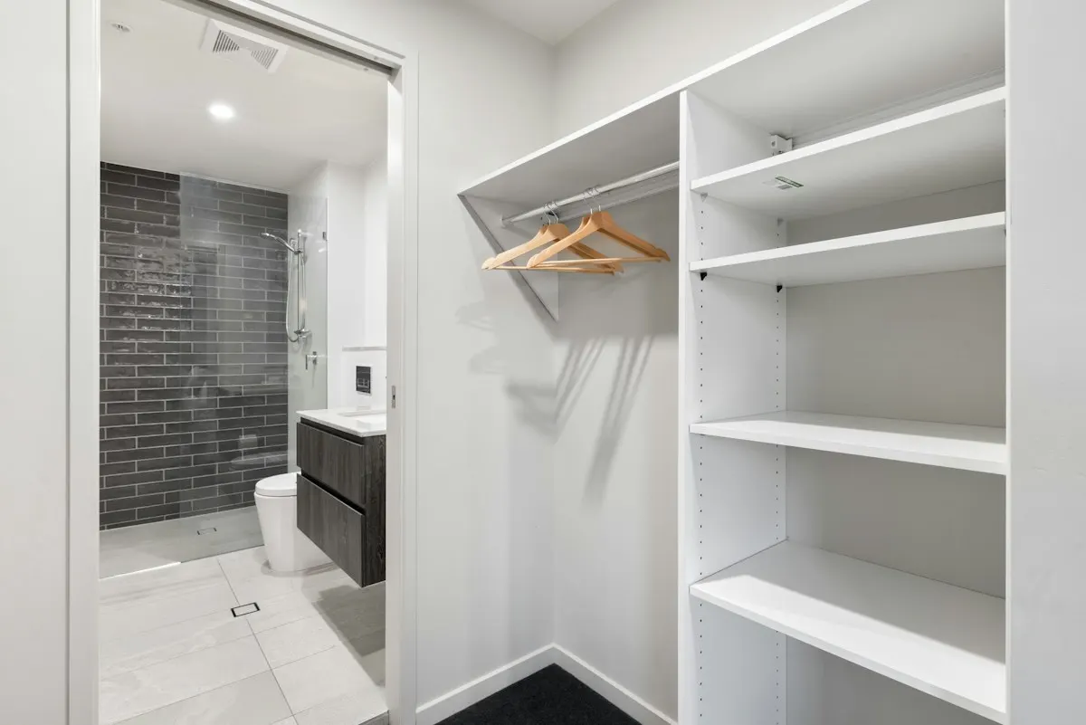 White wardrobe shelving and hanging rail beside a bathroom